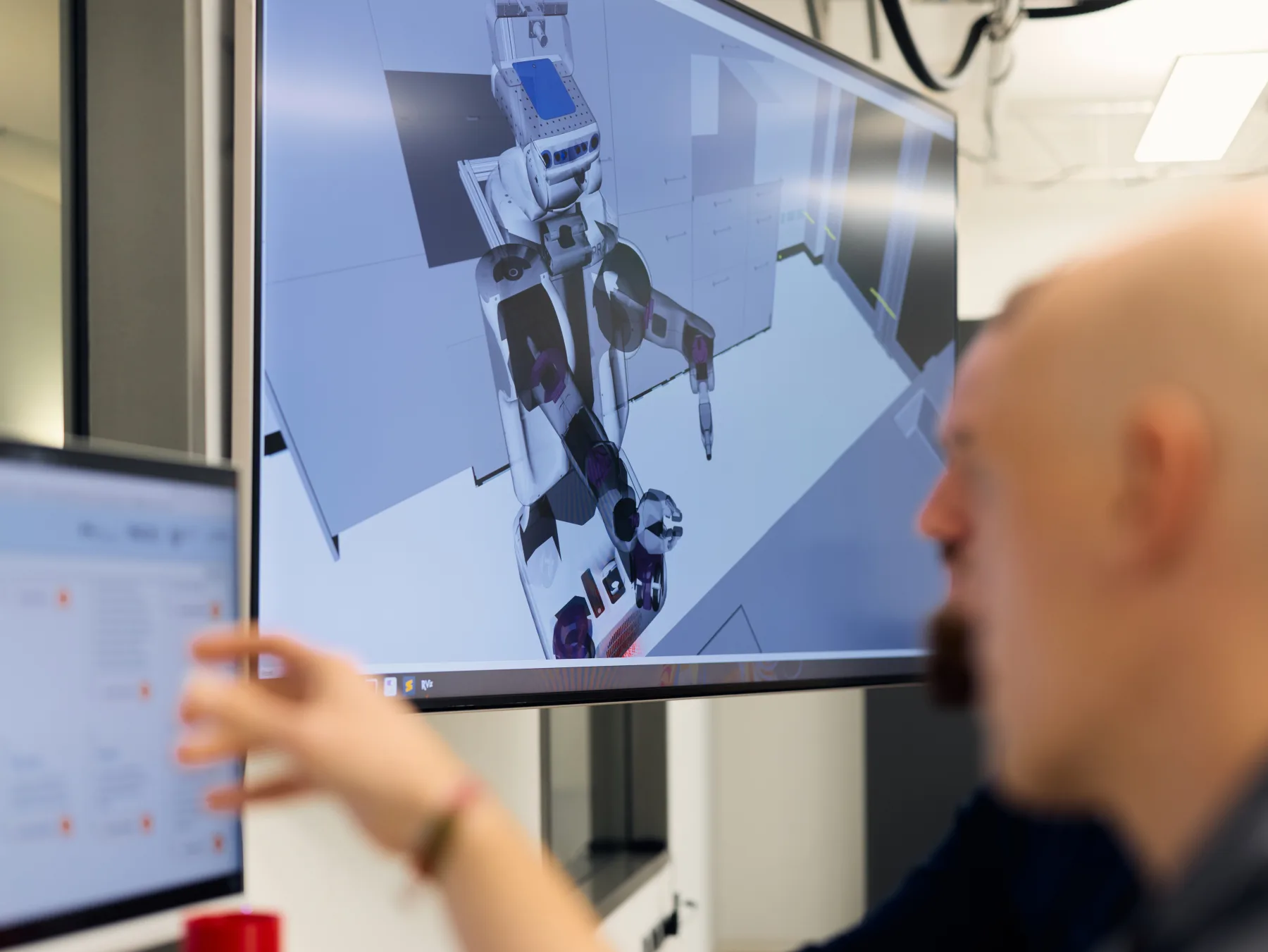 A researcher reviewing a simulated robot task on a large display